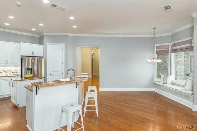 9533 Fendall Hall Cir, Montgomery, AL 36117 - kitchen with an island with sink, visible vents, a breakfast bar, and stainless steel refrigerator with ice dispenser