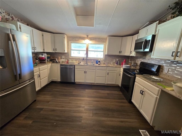 kitchen featuring dark wood-style floors, white cabinets, tasteful backsplash, and appliances with stainless steel finishes