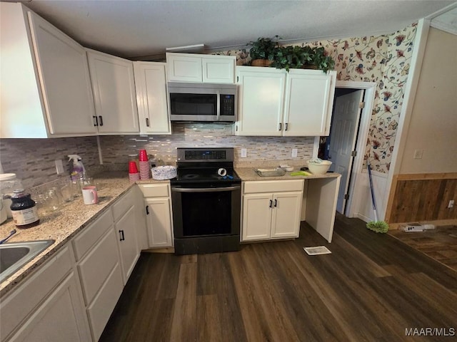 kitchen with a wainscoted wall, dark wood-style floors, white cabinetry, and stainless steel appliances