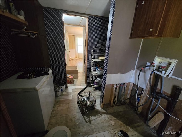 laundry room with washer hookup, cabinet space, and wallpapered walls