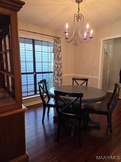 dining space with baseboards, dark wood-style flooring, a healthy amount of sunlight, and an inviting chandelier