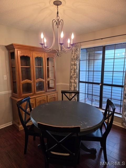 dining area featuring dark wood-style flooring, a notable chandelier, baseboards, and plenty of natural light