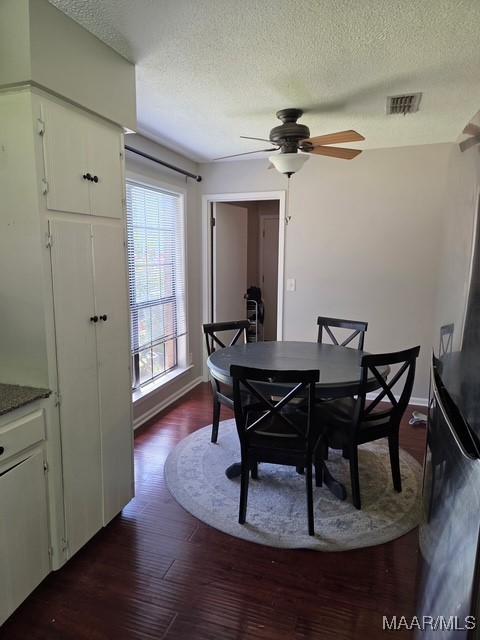 dining room with a ceiling fan, a textured ceiling, baseboards, dark wood-style flooring, and visible vents