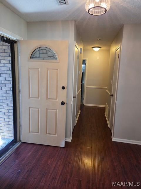 corridor with baseboards, visible vents, and dark wood-style floors