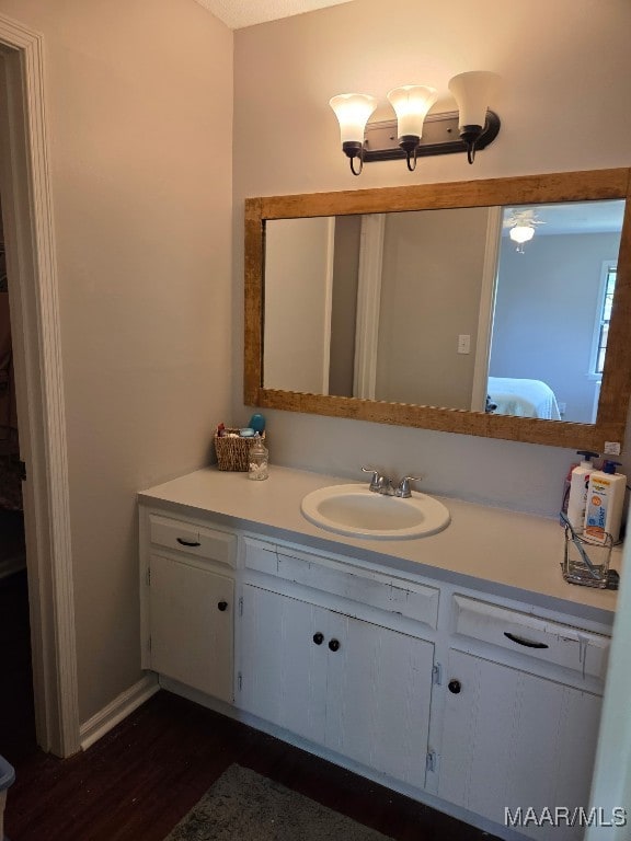 ensuite bathroom featuring ensuite bath, vanity, and wood finished floors