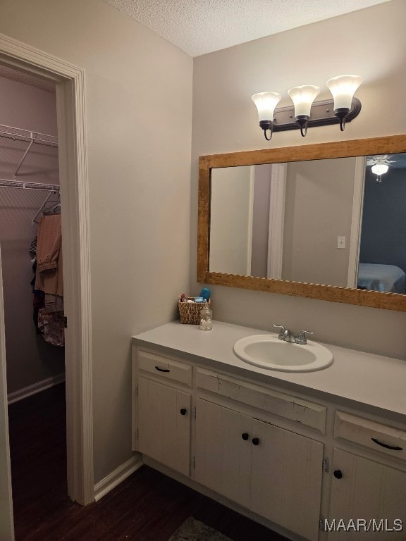 bathroom featuring a spacious closet, vanity, a textured ceiling, and wood finished floors