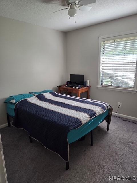 bedroom with a textured ceiling, baseboards, a ceiling fan, and carpet floors
