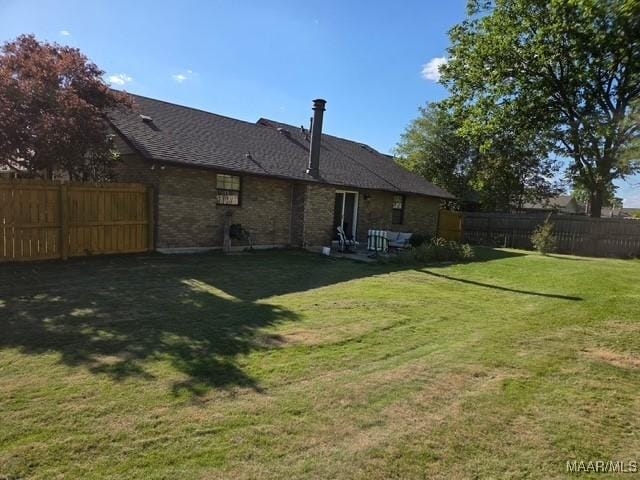 rear view of house with a lawn and a fenced backyard