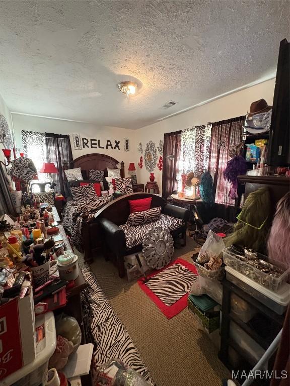 bedroom featuring carpet floors, multiple windows, a textured ceiling, and visible vents