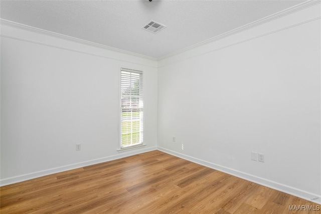 empty room with visible vents, ornamental molding, baseboards, light wood-style flooring, and a textured ceiling