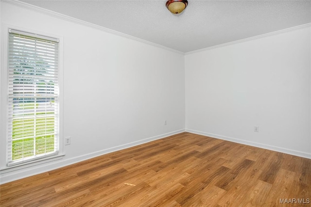 spare room with wood finished floors, a textured ceiling, crown molding, and baseboards