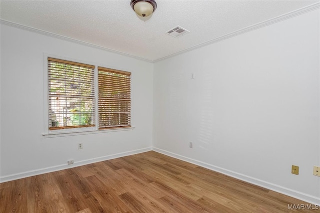 unfurnished room with a textured ceiling, light wood-type flooring, visible vents, and crown molding