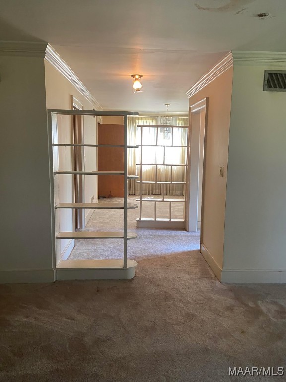 carpeted spare room with visible vents, baseboards, a chandelier, and crown molding