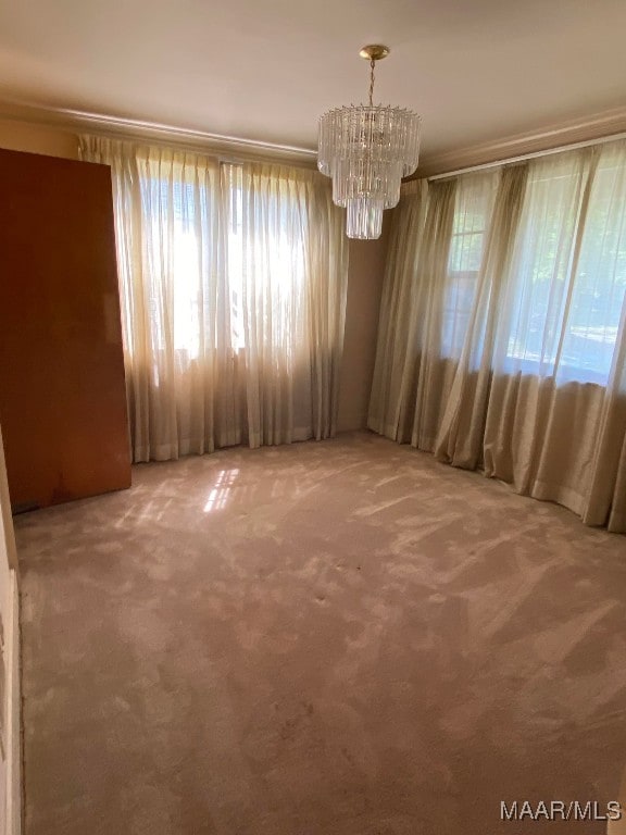 unfurnished dining area featuring a healthy amount of sunlight, carpet flooring, and a chandelier
