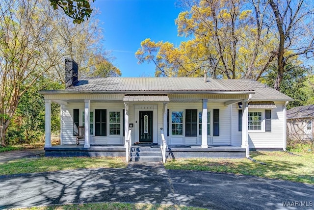 view of front of property with metal roof, covered porch, and a chimney