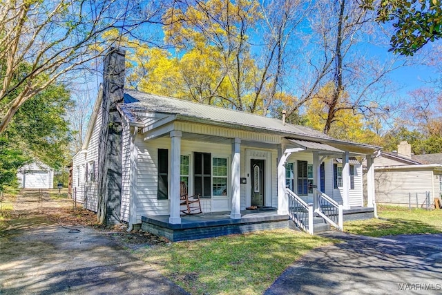 view of front of property featuring a porch, an outdoor structure, a chimney, and metal roof