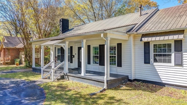 exterior space with a chimney, covered porch, and metal roof
