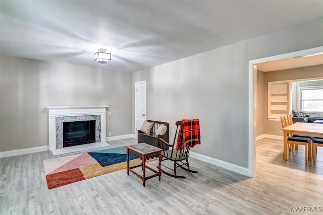 sitting room with wood finished floors, a fireplace, and baseboards