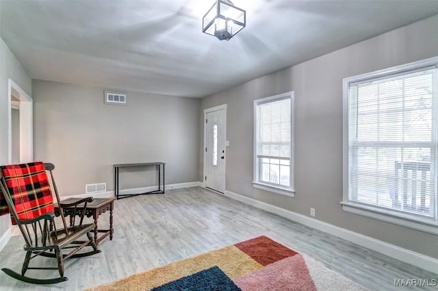entryway with wood finished floors, baseboards, and visible vents