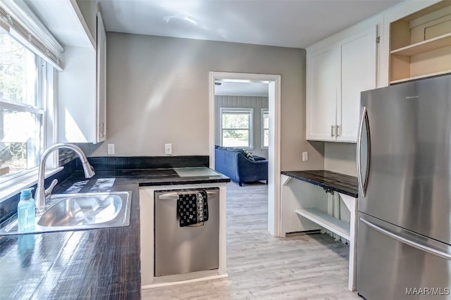 kitchen featuring open shelves, dark countertops, white cabinets, appliances with stainless steel finishes, and a sink