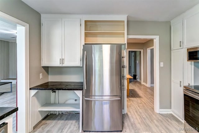 kitchen featuring baseboards, dark countertops, appliances with stainless steel finishes, light wood-style floors, and white cabinetry