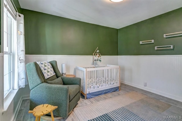 bedroom with wainscoting and wood finished floors