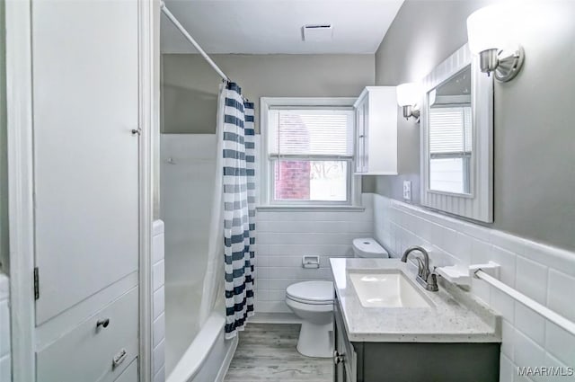bathroom with vanity, tile walls, toilet, and wainscoting