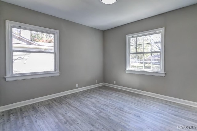 spare room with baseboards and wood finished floors