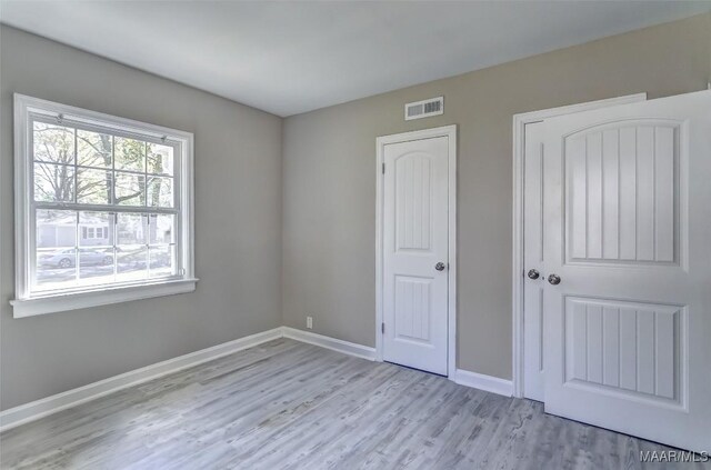 unfurnished bedroom featuring visible vents, baseboards, and wood finished floors