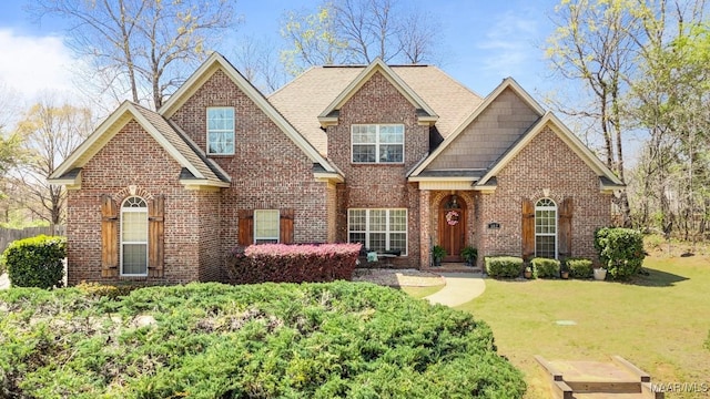 craftsman inspired home featuring brick siding, a front yard, and roof with shingles