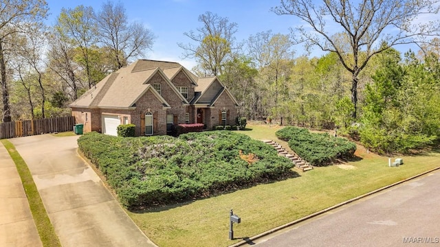 view of front of house featuring brick siding, a front lawn, fence, and driveway