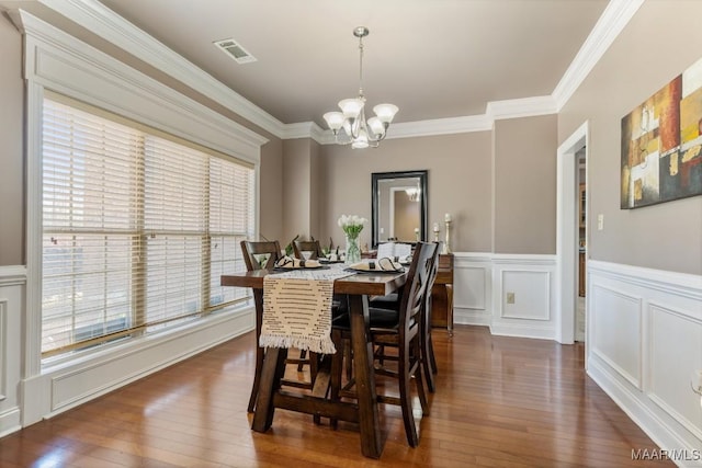 dining room with visible vents, dark wood-type flooring, a decorative wall, and a chandelier
