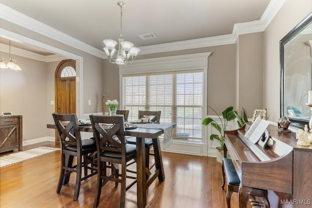 dining space with crown molding, wood finished floors, and a notable chandelier
