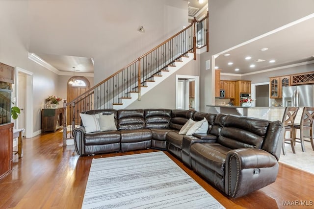 living room with crown molding, light wood-style floors, stairs, recessed lighting, and baseboards