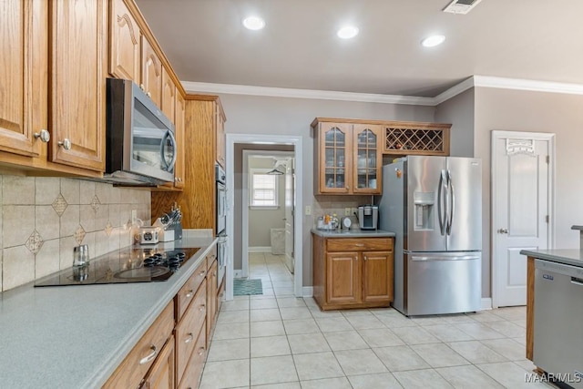 kitchen with decorative backsplash, light countertops, light tile patterned floors, glass insert cabinets, and stainless steel appliances