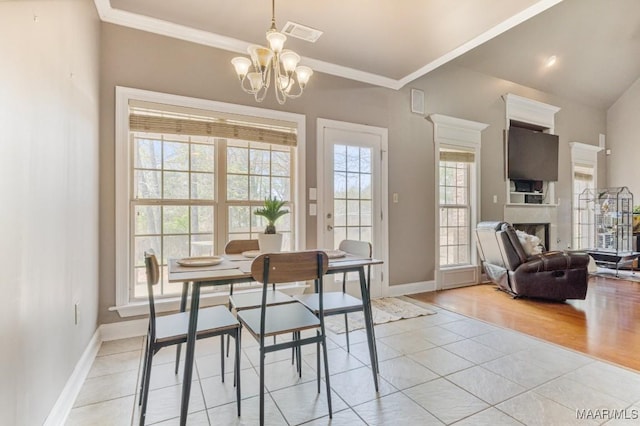 dining area featuring a fireplace, light tile patterned floors, baseboards, a chandelier, and ornamental molding