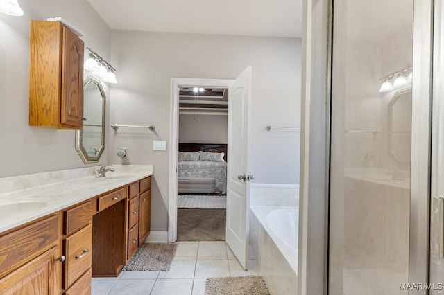ensuite bathroom with double vanity, a bath, a sink, tile patterned floors, and ensuite bath