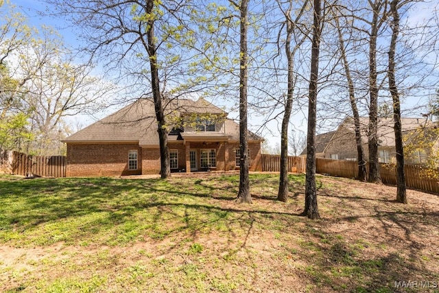 back of property featuring a lawn, brick siding, and a fenced backyard
