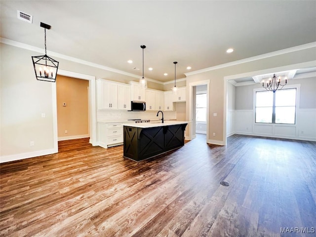 228 Mountain Laurel Rdg, Wetumpka, AL 36093 - kitchen featuring a notable chandelier, light countertops, wood finished floors, stainless steel microwave, and white cabinetry