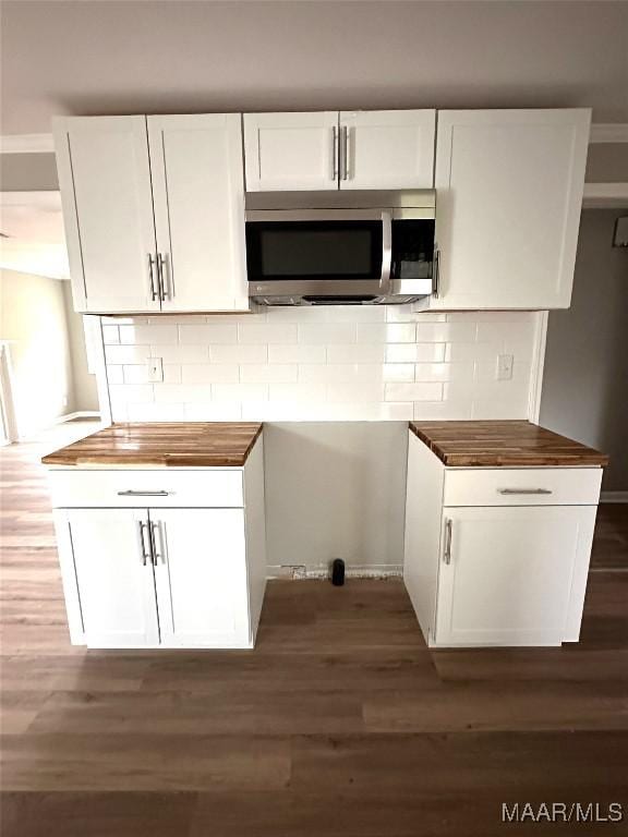 kitchen featuring butcher block countertops, stainless steel microwave, and dark wood-style flooring