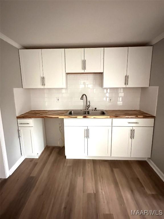 kitchen featuring a sink, backsplash, white cabinetry, and dark wood-style flooring