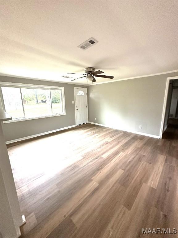 unfurnished room featuring a textured ceiling, a ceiling fan, visible vents, wood finished floors, and baseboards