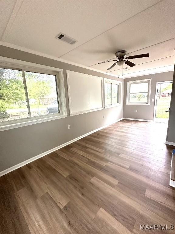 spare room featuring visible vents, ceiling fan, wood finished floors, and baseboards