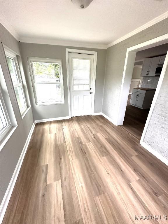 interior space with baseboards, ornamental molding, and wood finished floors