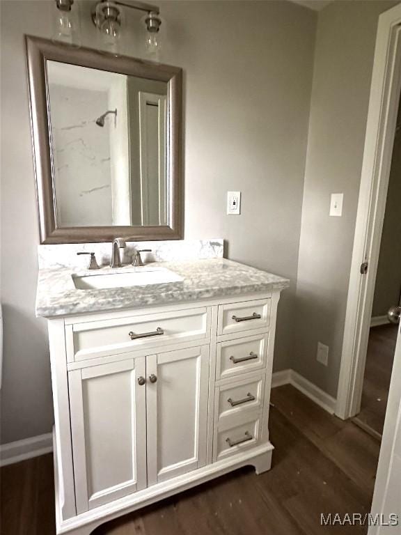 bathroom with baseboards, vanity, and wood finished floors