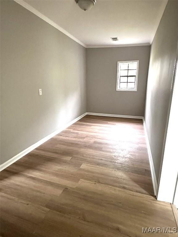 unfurnished room with crown molding, visible vents, baseboards, and wood finished floors