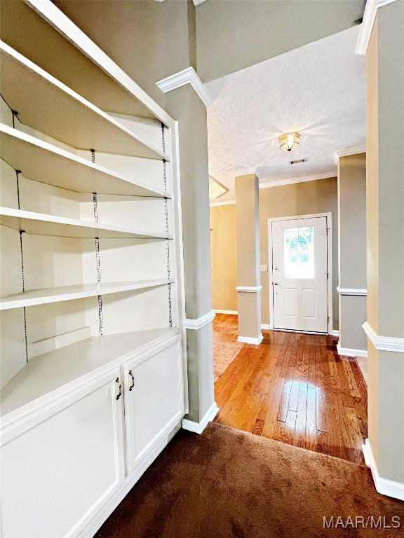 foyer entrance featuring hardwood / wood-style floors, crown molding, baseboards, and a textured ceiling
