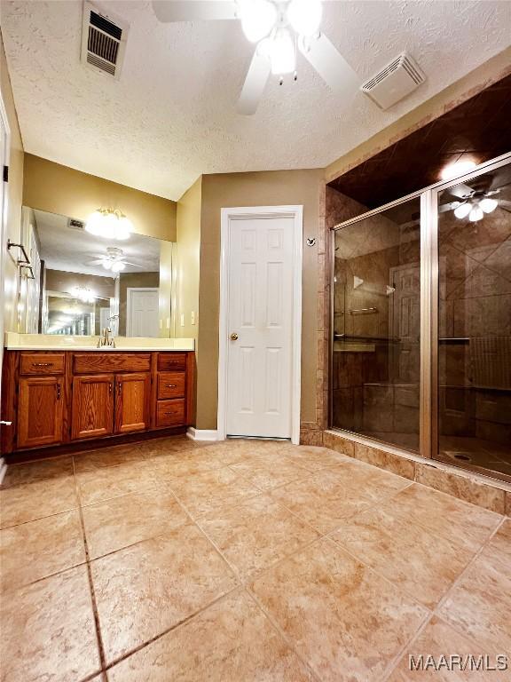 full bath featuring a shower stall, a textured ceiling, visible vents, and a ceiling fan