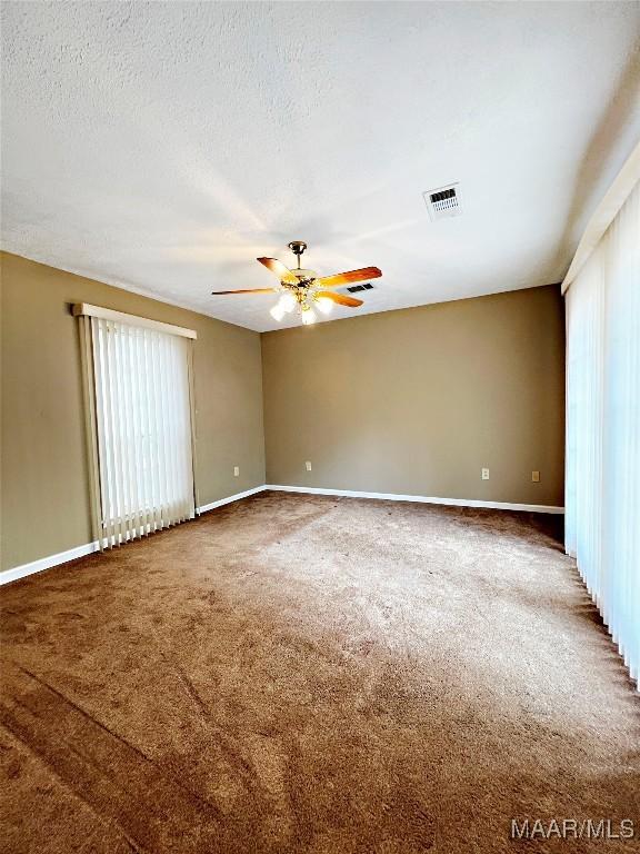 unfurnished room with carpet floors, a textured ceiling, baseboards, visible vents, and ceiling fan