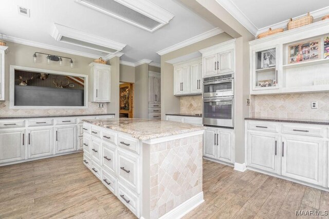 2714 County Road 54, Ozark, AL 36360 - kitchen with double oven, light stone countertops, ornamental molding, and light wood finished floors